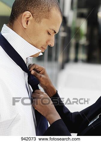 Stock Image - A businesswoman tying her boyfriend's tie. Fotosearch