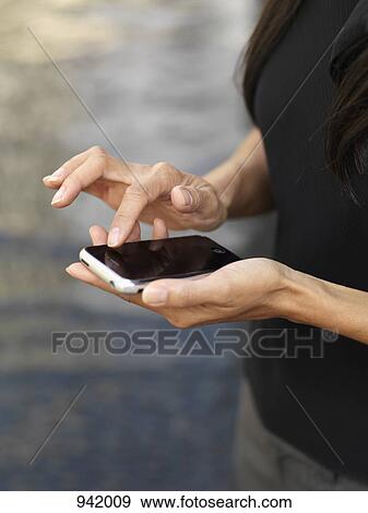 A businesswoman using a smart phone, midsection, focus on hands View Large Photo Image Stock Photo - A businesswoman using a smart phone, midsection, focus on hands. Fotosearch