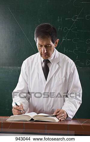 A chemistry teacher consulting a textbook in his classroom View Large Photo Image Picture - A chemistry teacher consulting a textbook in his classroom. Fotosearch