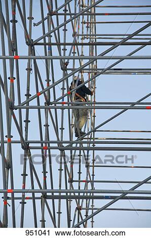 A construction worker standing on scaffolding View Large Photo Image Stock Image - A construction worker standing on scaffolding. Fotosearch