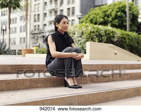A contemplative businesswoman sitting on the outdoor steps of an office complex View Large Photo Image Picture - A contemplative businesswoman sitting on the outdoor steps of an office complex. Fotosearch