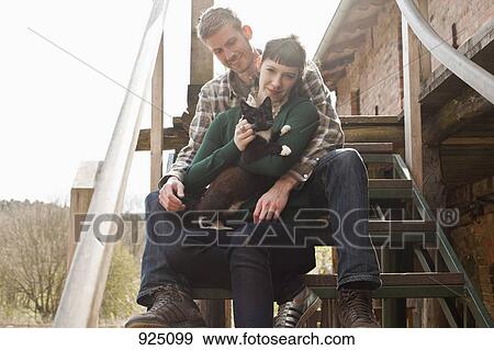 Stock Photo - A couple holding and petting a cat. Fotosearch