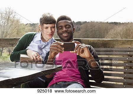 Stock Photo - A couple looking at a smartphone together. Fotosearch