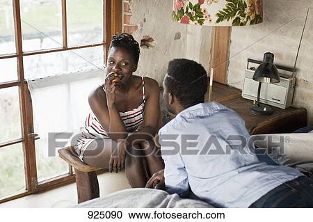 Stock Image - A couple relaxing in their bedroom. Fotosearch
