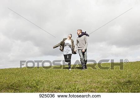 A couple running down a hill while holding hands View Large Photo Image Stock Photograph - A couple running down a hill while holding hands. Fotosearch