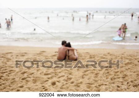 Picture - A couple sitting at the beach, defocused. Fotosearch