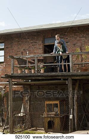 Stock Image - A couple standing on a balcony looking into the distance. Fotosearch
