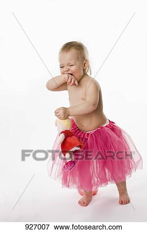 Stock Photo - A crying toddler wearing a tutu and holding a stuffed toy, studio shot. Fotosearch