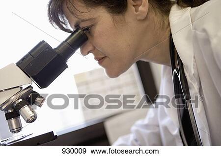 A doctor looking through a microscope View Large Photo Image Stock Photo - A doctor looking through a microscope. Fotosearch