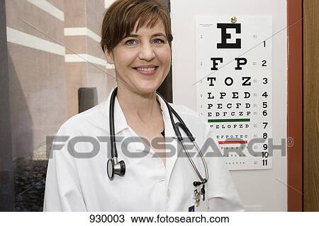 Stock Image - A doctor standing in front of an eye chart, smiling. Fotosearch