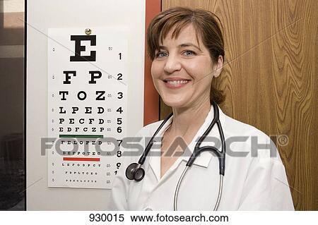 Stock Photography - A doctor standing in front of an eye chart, smiling. Fotosearch