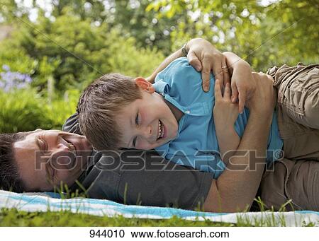 A father embracing his son on a lawn View Large Photo Image Stock Image - A father embracing his son on a lawn. Fotosearch