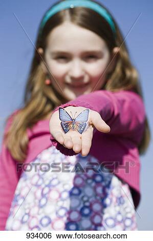 Stock Photograph - A girl holding a plastic butterfly in her hand. Fotosearch