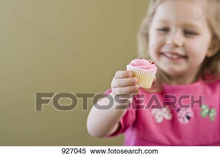 Stock Photography - A girl holding out a cupcake, focus on hand. Fotosearch
