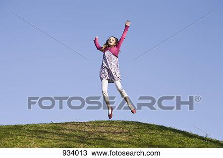 A girl jumping on a grassy hill View Large Photo Image Stock Image - A girl jumping on a grassy hill. Fotosearch