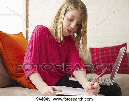 A girl sitting on a sofa with a laptop and writing in a notebook View Large Photo Image Stock Photography - A girl sitting on a sofa with a laptop and writing in a notebook. Fotosearch