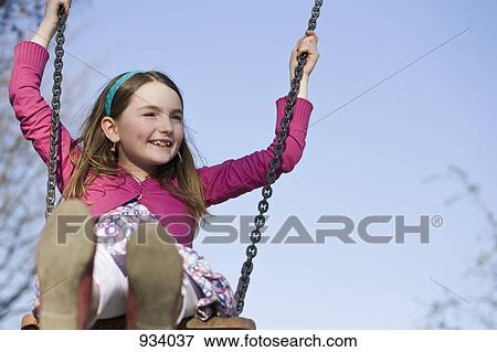 A girl sitting on a swing View Large Photo Image Stock Photo - A girl sitting on a swing. Fotosearch