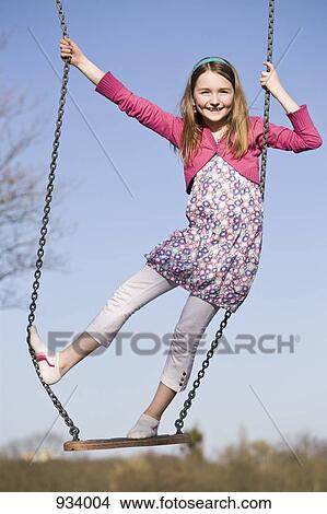 Picture - A girl standing on a swing. Fotosearch