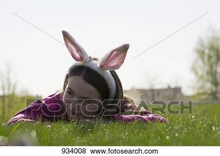 A girl wearing rabbit ears and lying down on grass View Large Photo Image Stock Photo - A girl wearing rabbit ears and lying down on grass. Fotosearch