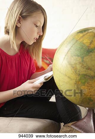 A girl writing in a notepad while sitting next to a world globe View Large Photo Image Stock Photo - A girl writing in a notepad while sitting next to a world globe. Fotosearch