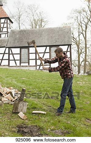 Stock Photograph - A man chopping wood in a rural setting. Fotosearch