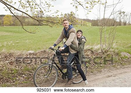 A man giving a ride to his girlfriend on a bicycle in the country View Large Photo Image Stock Image - A man giving a ride to his girlfriend on a bicycle in the country. Fotosearch