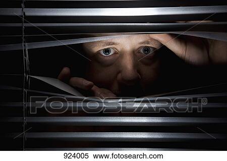 Stock Photography - A man peeking through blinds. Fotosearch
