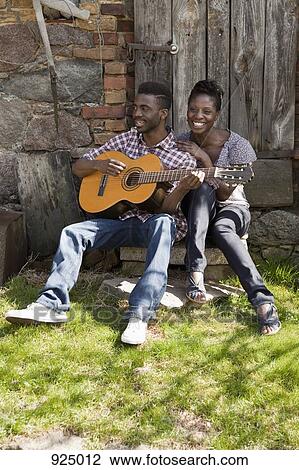 Stock Image - A man playing an acoustic guitar with his girlfriend. Fotosearch