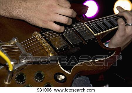 Stock Photograph - A man playing an electric guitar, close up of hands. Fotosearch
