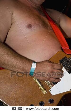 Stock Image - A man playing an electric guitar shirtless. Fotosearch