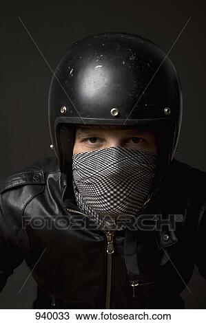 Stock Image - A man wearing a helmet and a bandana mask. Fotosearch