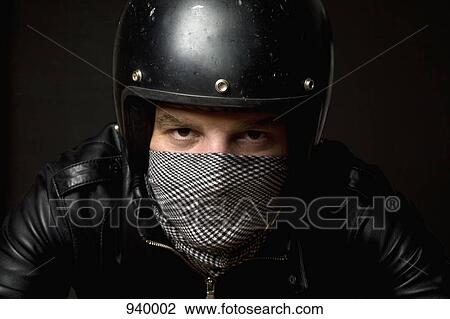 Stock Image - A man wearing a helmet, bandana mask and leather jacket. Fotosearch