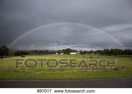 Stock Photo - A rainbow in the sky over a rural setting. Fotosearch