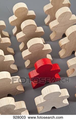 Stock Image - A red wooden stick figure with a group of unpainted wooden stick figures. Fotosearch