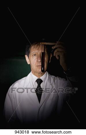 Stock Photo - A scientist looking at a test tube of liquid. Fotosearch