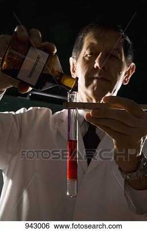Stock Photograph - A scientist pouring liquid into a test tube. Fotosearch