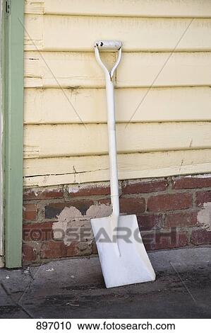 A shovel leaning against a wall View Large Photo Image Stock Image - A shovel leaning against a wall. Fotosearch