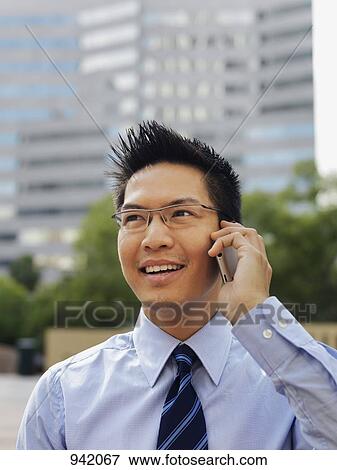 A smiling businessman using a mobile phone View Large Photo Image Stock Photo - A smiling businessman using a mobile phone. Fotosearch
