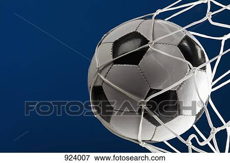 Stock Photo - A soccer ball in a net, close-up. Fotosearch