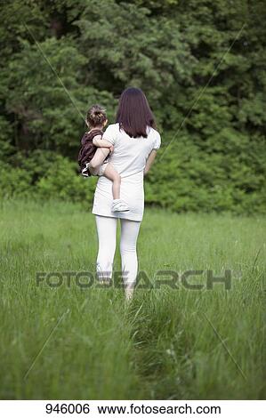 A woman holding her young daughter, rear view, outdoors View Large Photo Image Stock Photograph - A woman holding her young daughter, rear view, outdoors. Fotosearch