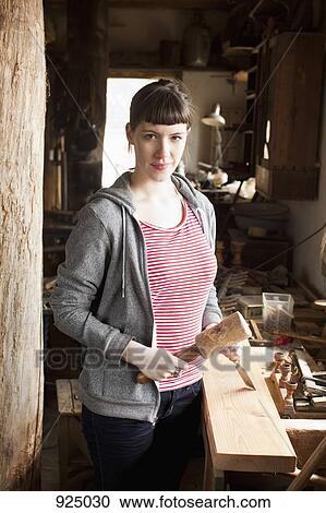 A woman in a workshop holding a chisel and mallet View Large Photo Image Stock Image - A woman in a workshop holding a chisel and mallet . Fotosearch