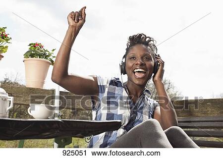 Stock Image - A woman listening to headphones, singing and dancing. Fotosearch