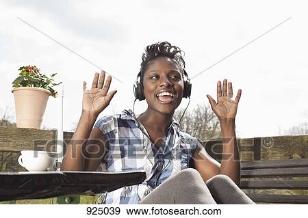 Stock Photo - A woman wearing headphones singing and dancing. Fotosearch
