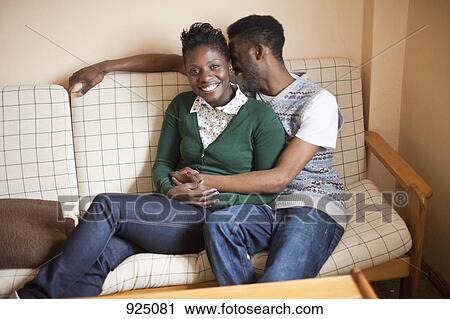 Stock Image - A young affectionate couple relaxing on a couch. Fotosearch