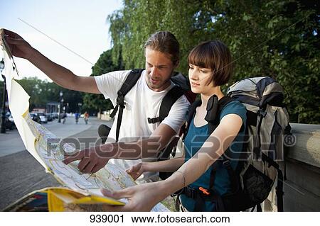 Stock Image - A young backpacker couple looking at a city map. Fotosearch