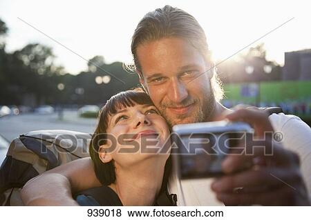 Stock Photo - A young backpacker couple taking a photograph of themselves. Fotosearch
