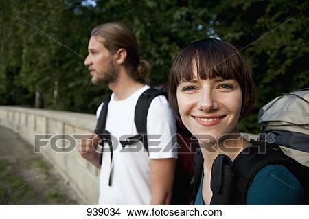 Picture - A young backpacker woman with her boyfriend, focus on woman. Fotosearch