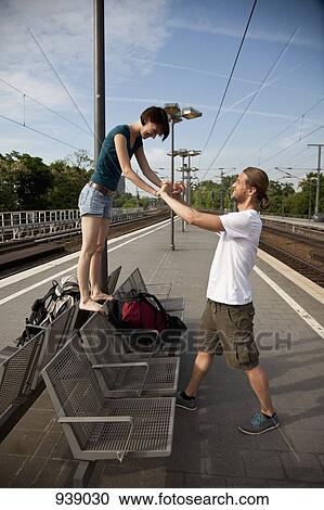 Stock Image - A young couple having fun while waiting on a train platform. Fotosearch
