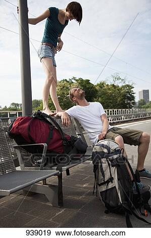Stock Photo - A young couple having fun while waiting on a train platform. Fotosearch