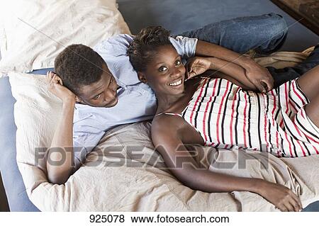 Stock Photo - A young couple relaxing in bed. Fotosearch